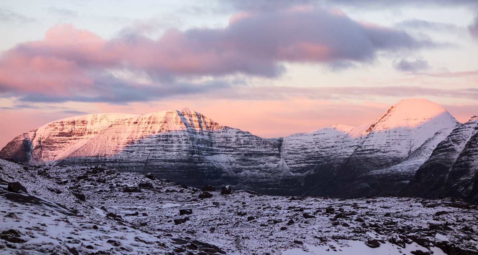 The pink light of daybreak hits the tops of Beinn Alligin