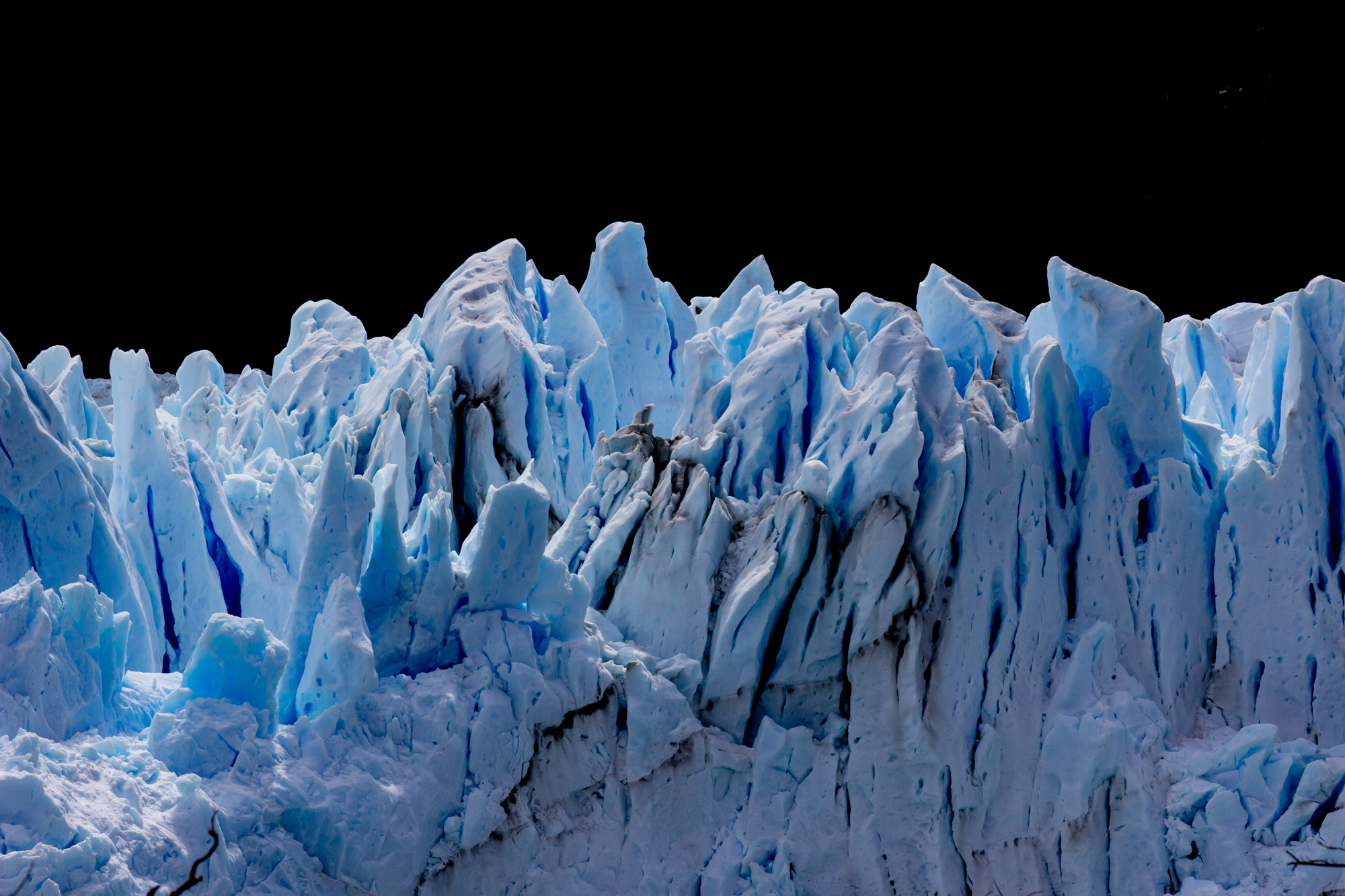 Stark contrasts on the Perito Moreno glacier as shafts of sunlight illuminate the tottering ice towers