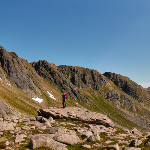 A panoramic photo of a person standing on a rock with Coire Sputan Dearg in the Cairngorms behind them