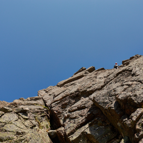 A climber on the first pitch of Amethyst Pillar on Grey Man's Crag in Coire Sputan Dearg in the Cairngorms in sunny weather