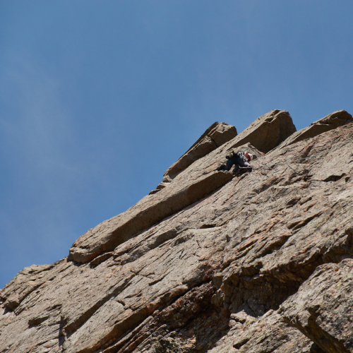 A climber high on the first pitch of Amethyst Pillar on Grey Man's Crag in Coire Sputan Dearg in the Cairngorms in sunny weather