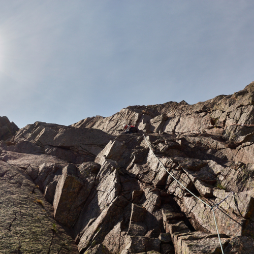 A climber on the first pitch of the rock climb Grey Slab in Coire Sputan Dearg in the Cairngorms on a sunny day