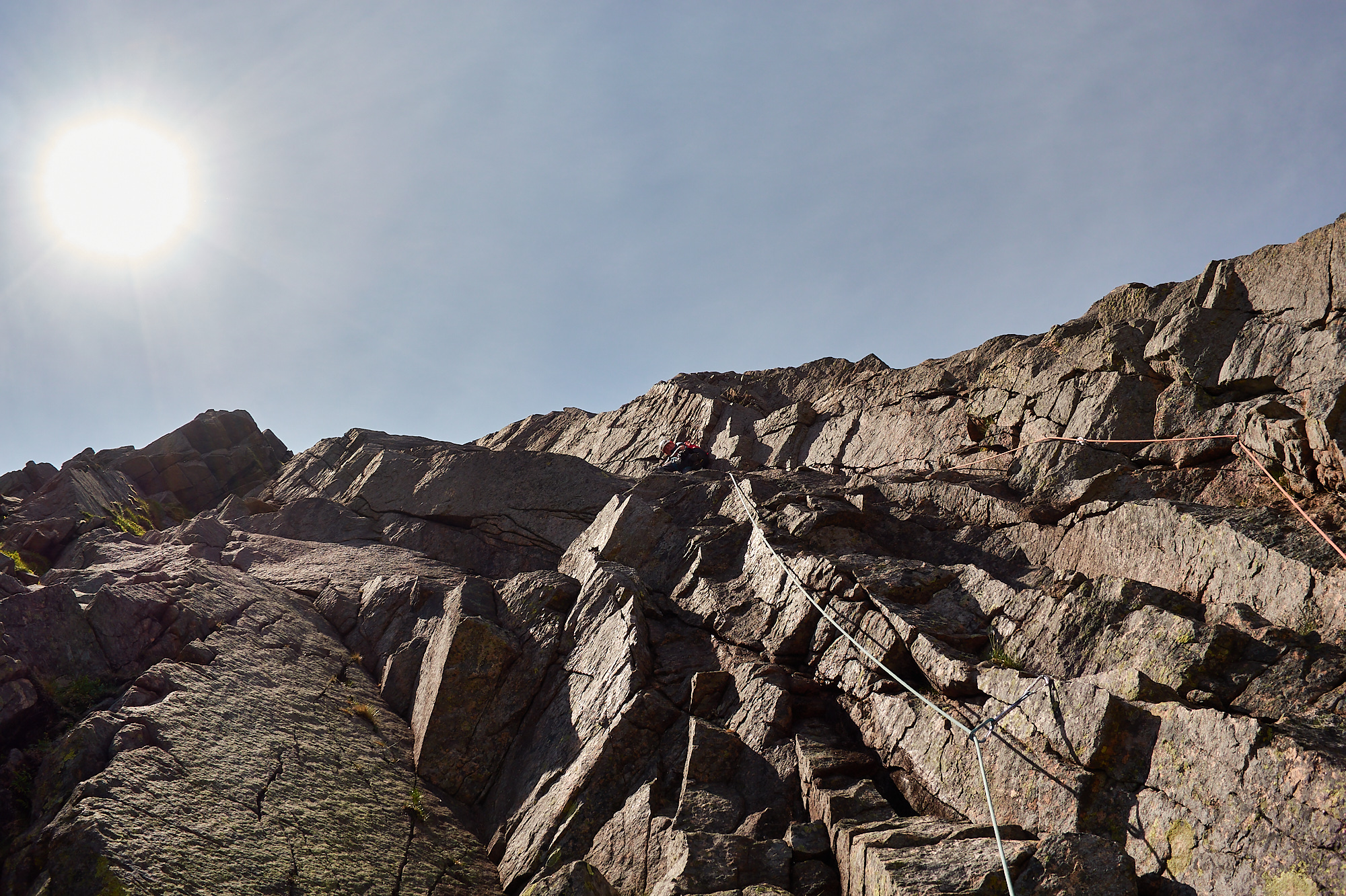 A climber on the first pitch of the rock climb Grey Slab in Coire Sputan Dearg in the Cairngorms on a sunny day