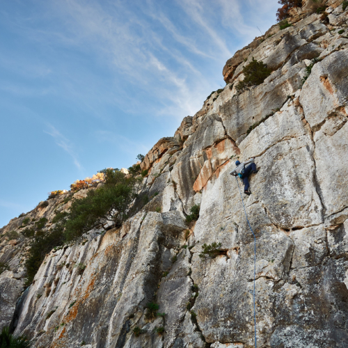 A climber sport climbing on a limestone crack in southern Spain with blue sky above