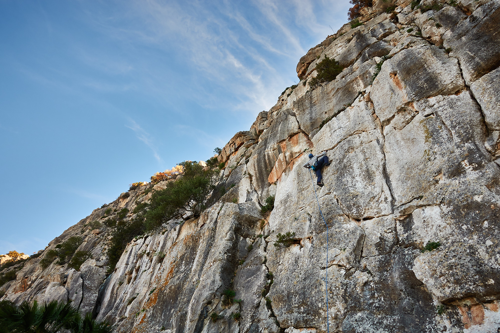 A climber sport climbing on a limestone crack in southern Spain with blue sky above