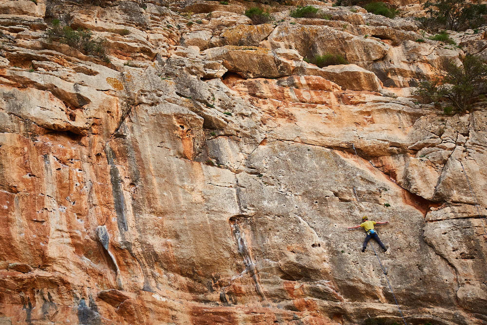 A climber sport climbing on a grey and orange limestone cliff in southern Spain with no hands on the rock