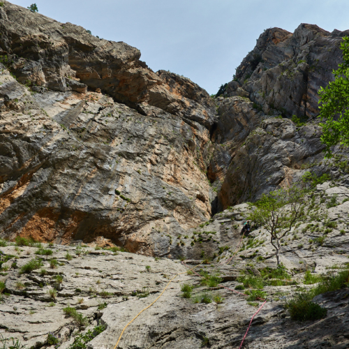 A climber on the first pitch of a route called Slovenski PIPS on a large limestone cliff called Debeli Kuk in the Paklenica gorge in Croatia