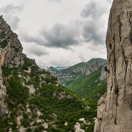 Two climbers abseiling off at the end of the first pitch on a large limestone buttress called Stup on Anica Kuk in the Paklenica gorge in Croatia