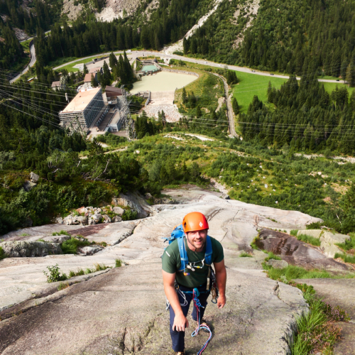 Looking down at a climber at the top of a sweep of clean granite slabs with the valley below